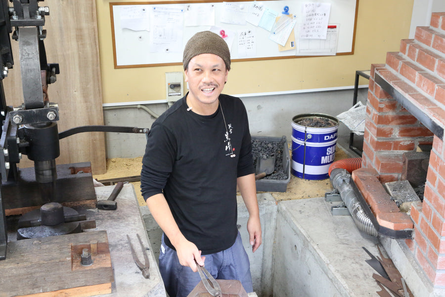 Yu Kurosaki holding tongs beside the power hammer in his Echizen forge
