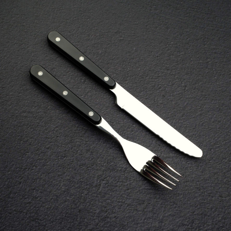 此 Santoku 刀長 180mm，重量 122g，適合切片、切丁與剁碎等工作，刀尖易於掌控，比牛刀來得不那麼銳利。八角橄欖木握柄提供穩固握感，無口環或夾片設計，便於精細操作。規格包括根部高度 49mm、脊厚在根部約 2.1mm，向前逐漸變薄至刀尖約 0.8mm，總長 278mm。SG2 鋼成分約含 1.25% 碳、14% 鉻、2.3% 鉬與 1.8% 釩，提供耐磨性與均勻碳化物分佈。