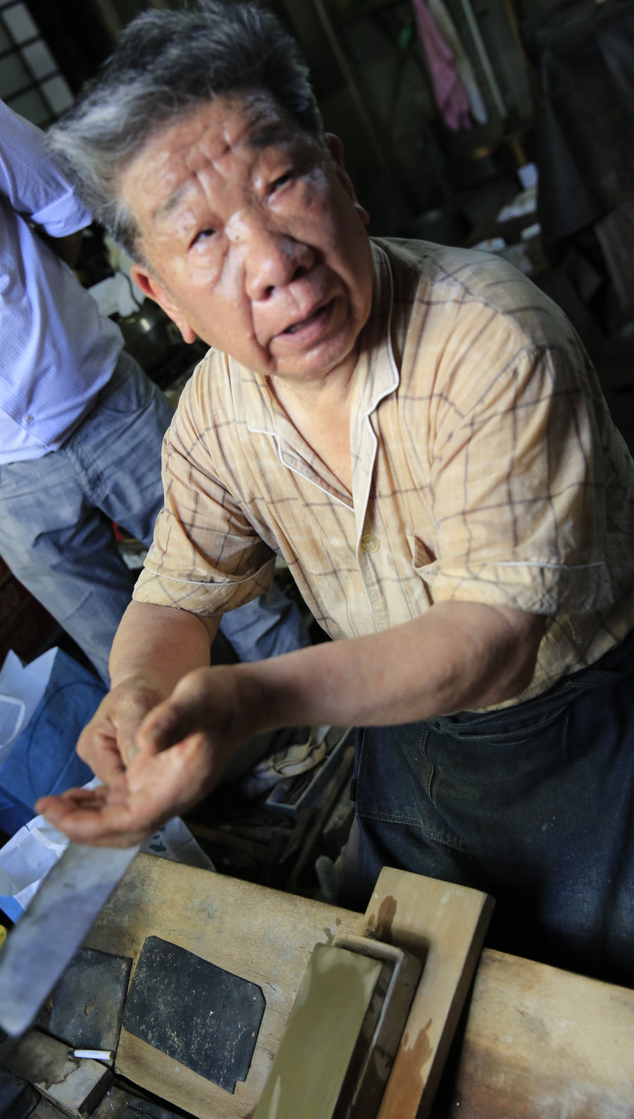 Yukinori Oda holds a finished blade over his whetstone bench, Sakai Takayuki workshop, 2014